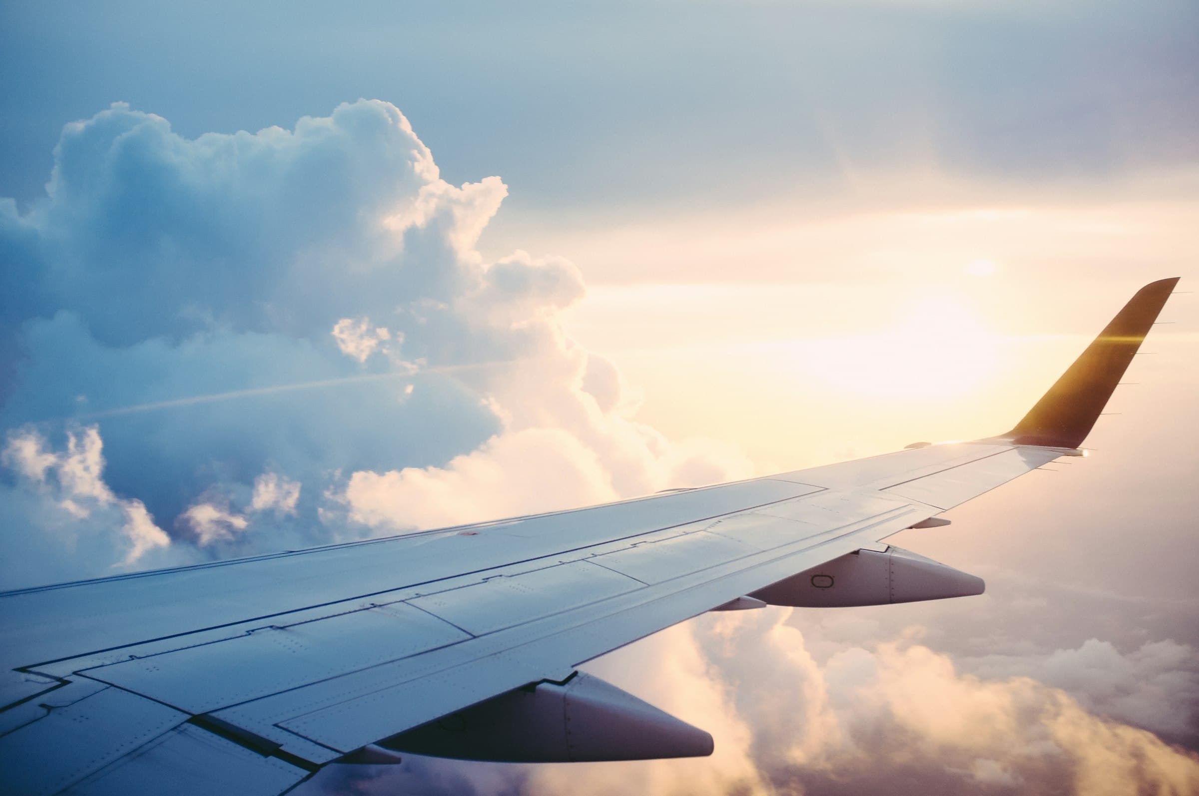 Aircraft wing above a sea of clouds at sunrise